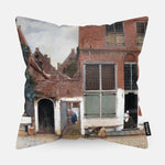 Kussen met schilderij van het straatje van een huis erop afgebeeld.