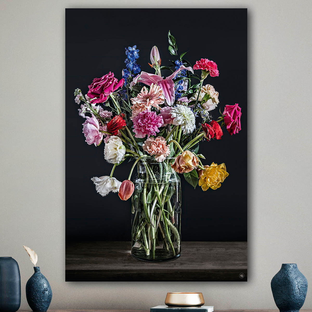 Schilderij met kleurrijke bloemen in een glazen vaas tegen een beige muur