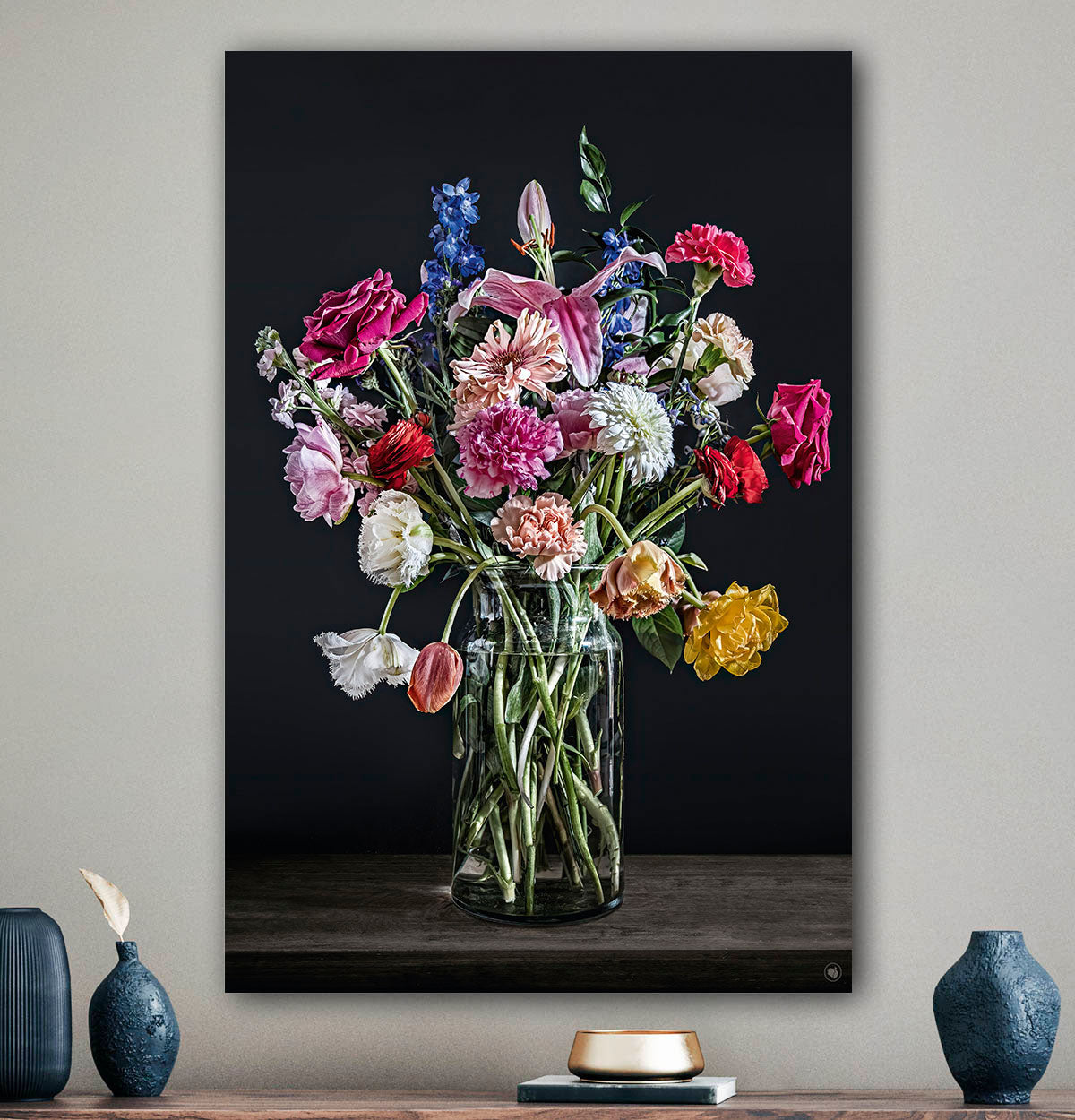 Schilderij met kleurrijke bloemen in een glazen vaas tegen een beige muur