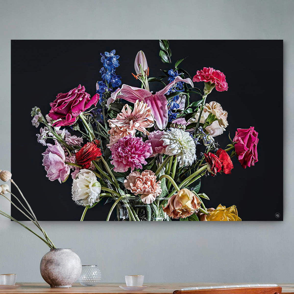 Schilderij met kleurrijke bloemen in een glazen vaas tegen een grijze muur