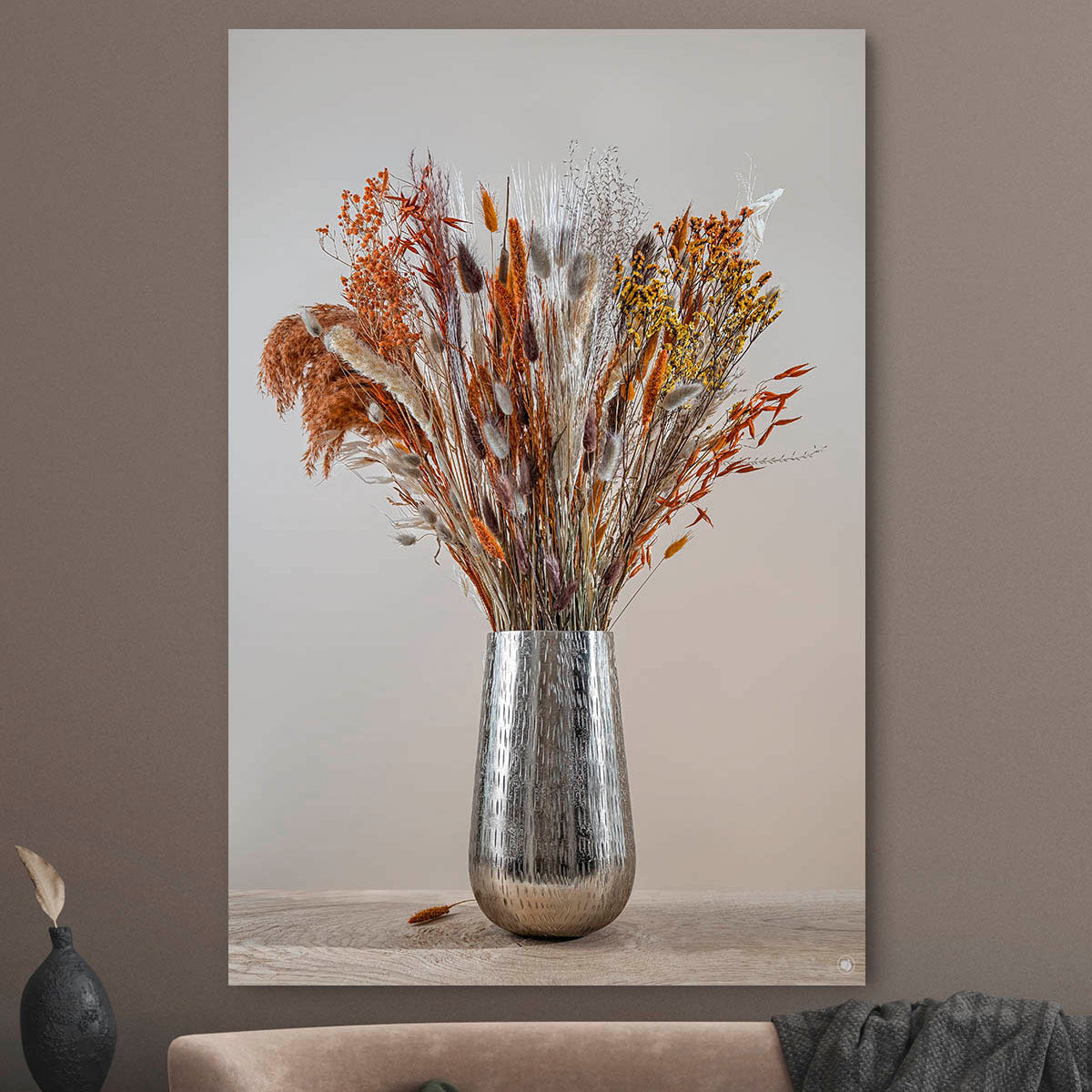 Schilderij met droogbloemen met koper kleur tegen een muur
