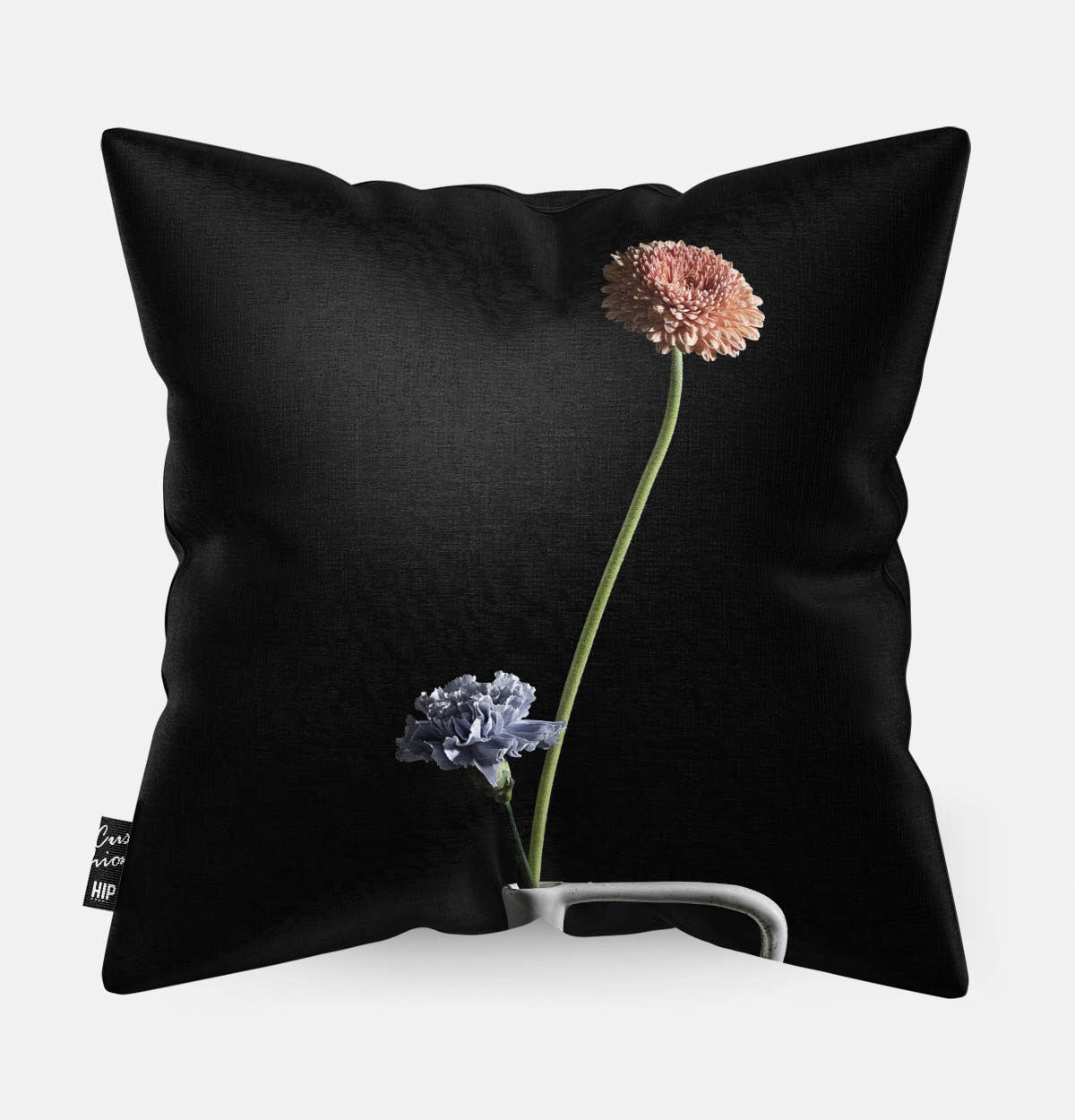Sierkussen met een wit vaasje met twee bloemen een donkere achtergrond