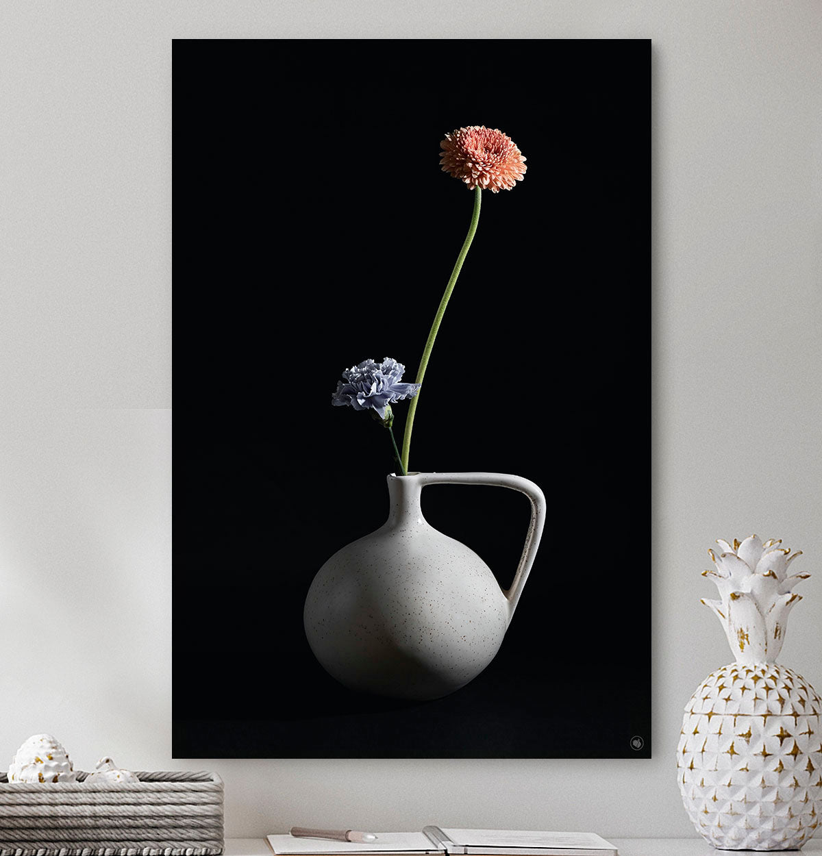 Schilderij met een vaasje met twee bloemen tegen een witte muur