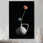Schilderij met een vaasje met twee bloemen tegen een witte muur