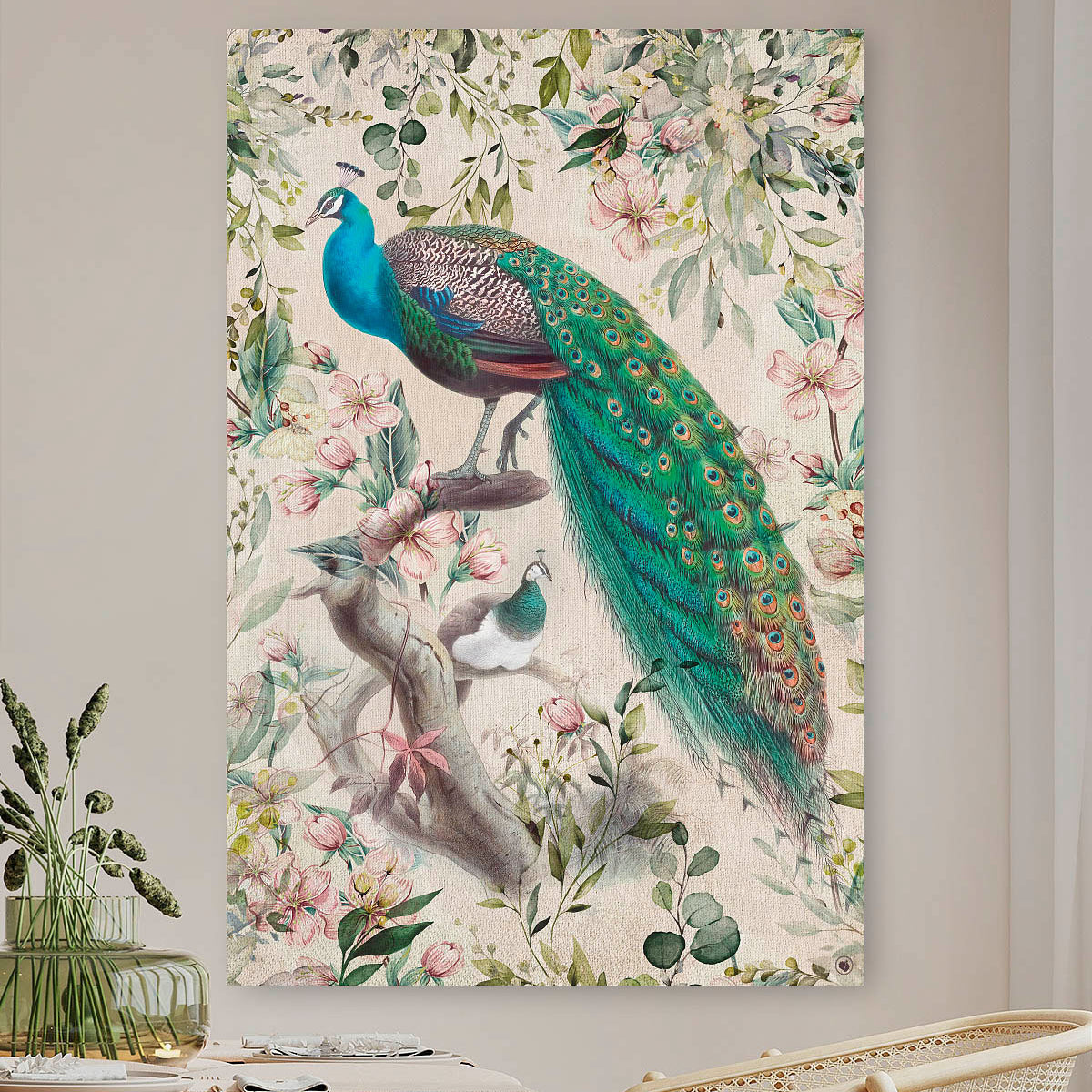 Schilderij met pauwen met een groene staart en roze bloemen tegen een beige muur en een stoel