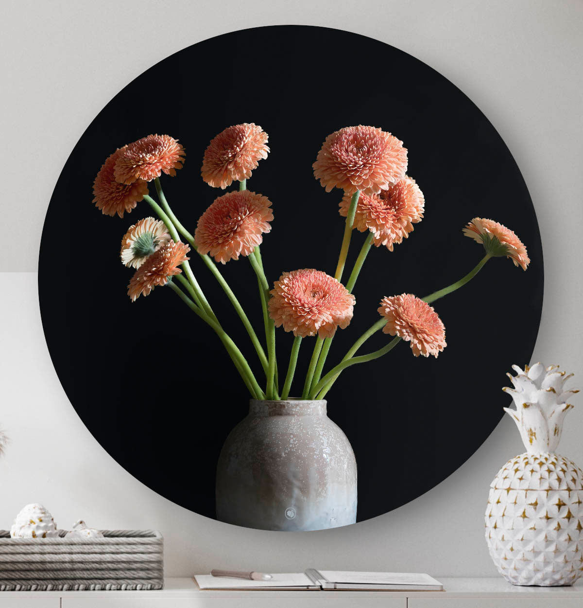 Wandcirkel met gerbera's en een grijze vaas met een zwarte achtergrond tegen een lichte muur