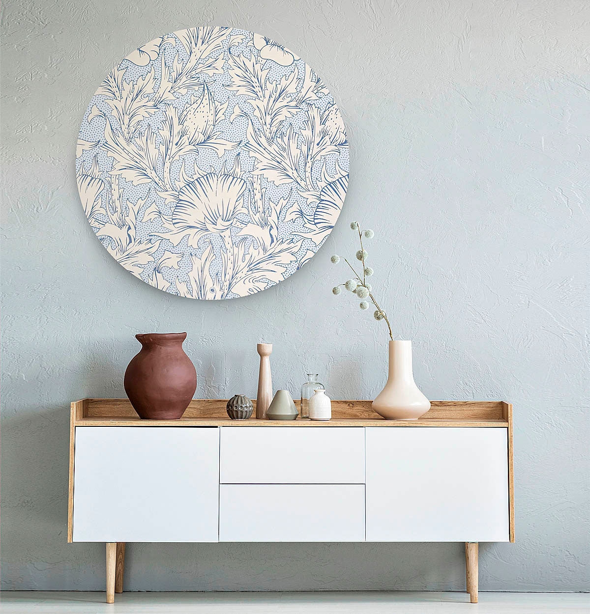Muurcirkel met blauw bloemenpatroon tegen een licht blauwe muur met een wit dressoir en vazen