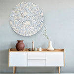 Muurcirkel met blauw bloemenpatroon tegen een licht blauwe muur met een wit dressoir en vazen