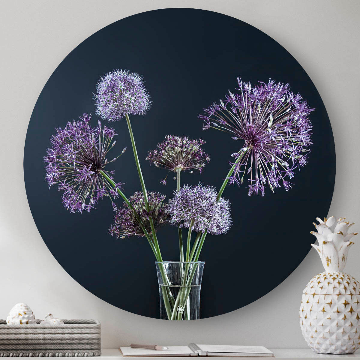 Muurcirkel met paarse bloemen en een zwarte achtergrond tegen een muur met een witte ananas