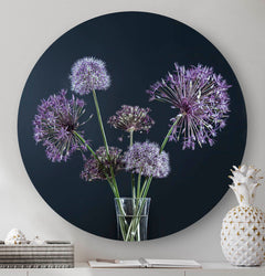Muurcirkel met paarse bloemen en een zwarte achtergrond tegen een muur met een witte ananas