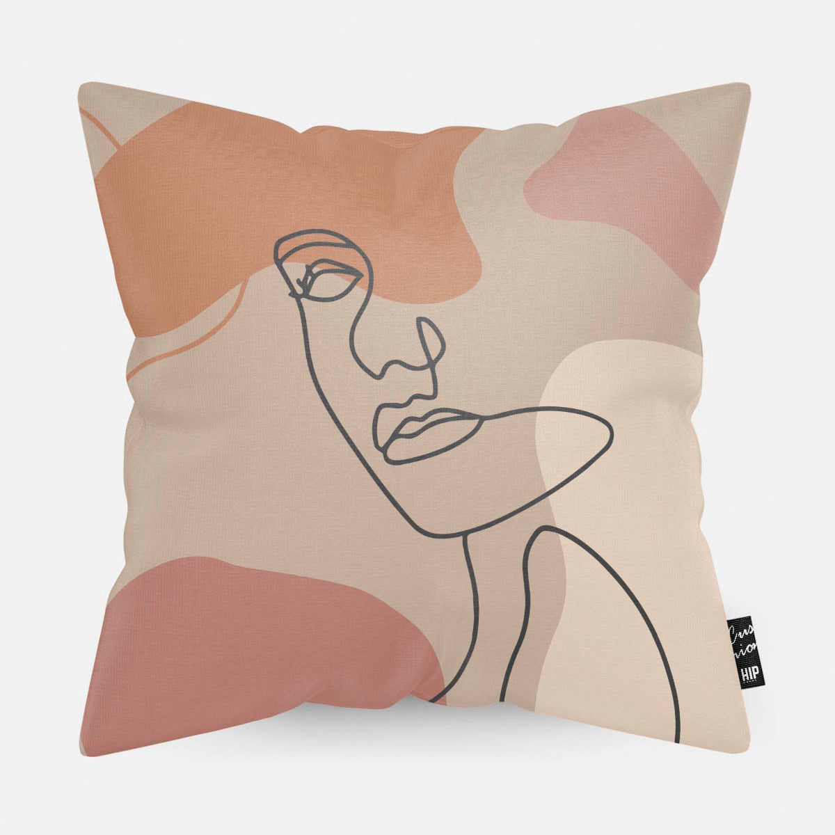 Kussen met line art met vrouwengezicht en verschillende roze vierkanten erop afgebeeld.