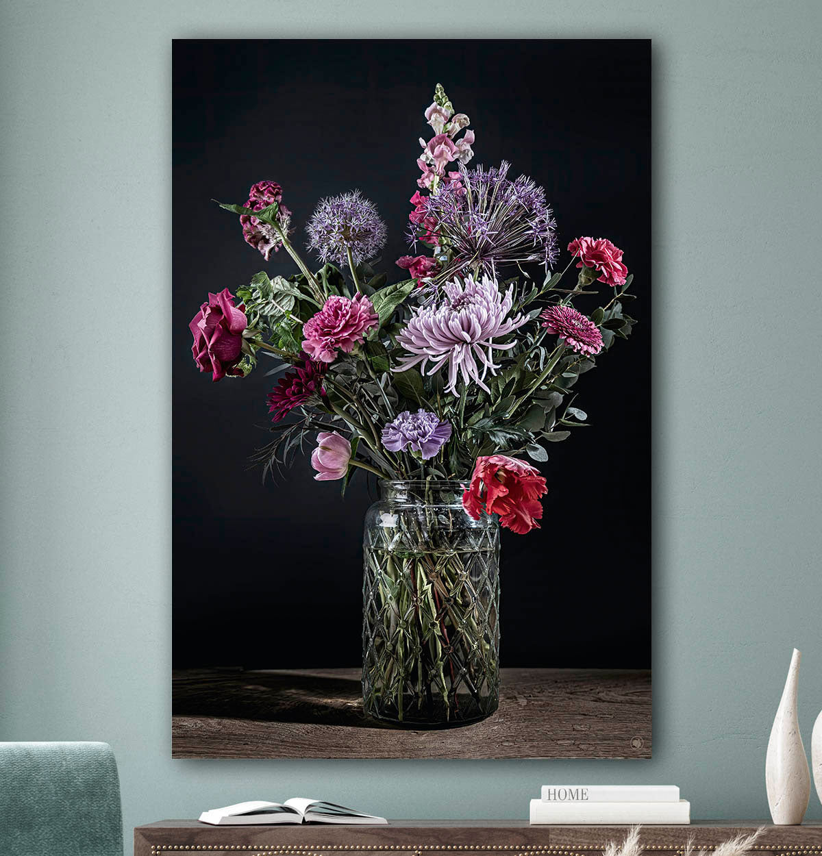 Schilderij met kleurrijke bloemen in een glazen vaas tegen een zacht groenemuur