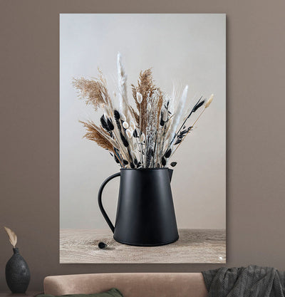 Schilderij met droogbloemen in zwart en beige tegen een beige muur