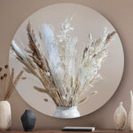 Wandcirkel met droogbloemen en pluimen tegen een licht bruine muur