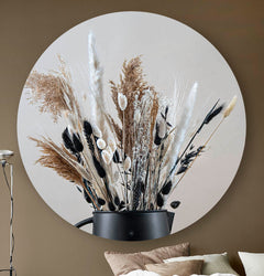 Wandcirkel met droogbloemen in zwart en beige tegen een beige muur