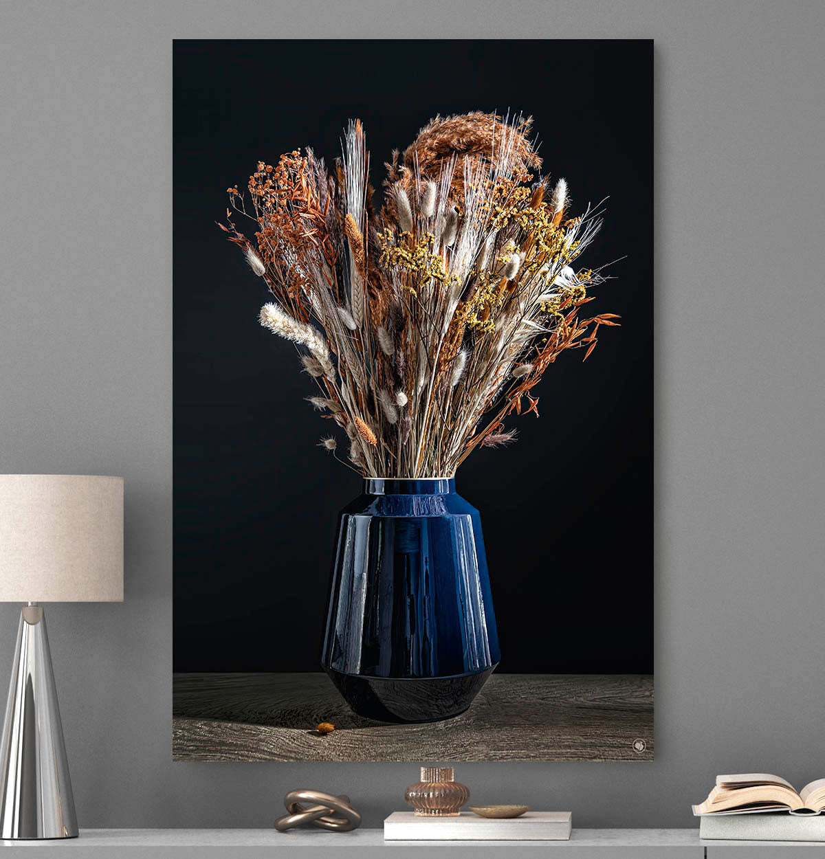 Schilderij met droogbloemen met koper kleur in een blauwe vaas tegen een grijze muur