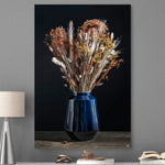 Schilderij met droogbloemen met koper kleur in een blauwe vaas tegen een grijze muur