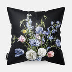Achterzijde van een sierkussen met lichtblauwe en witte bloemen met een donkere achtergrond
