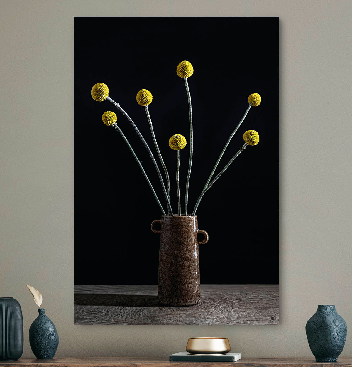 Schilderij met gele bol pluimen met een zwarte achtergrond tegen een beige muur