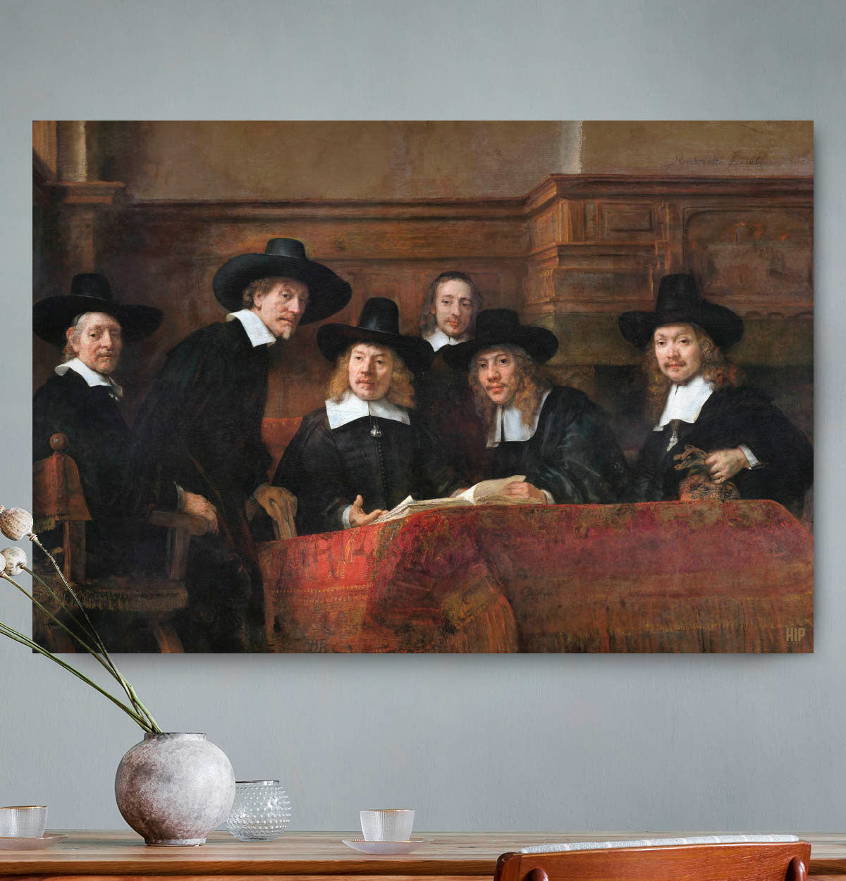 Vierkante wanddecoratie met schilderij van de staalmeesters erop.