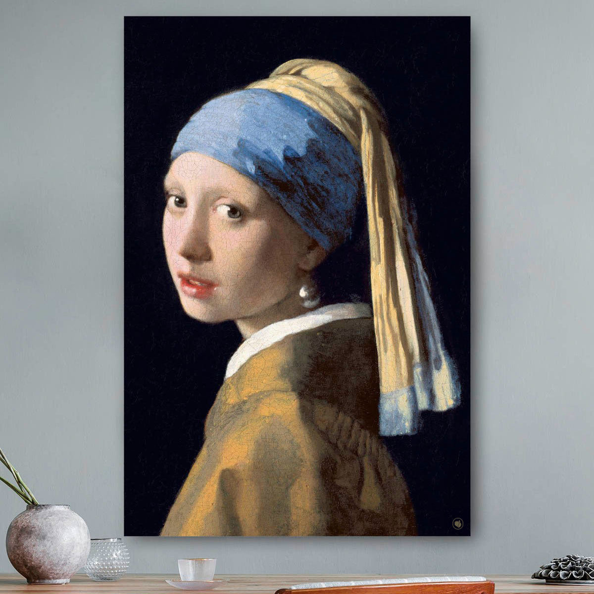 Vierkante wanddecoratie met schilderij van meisje met de parel erop.