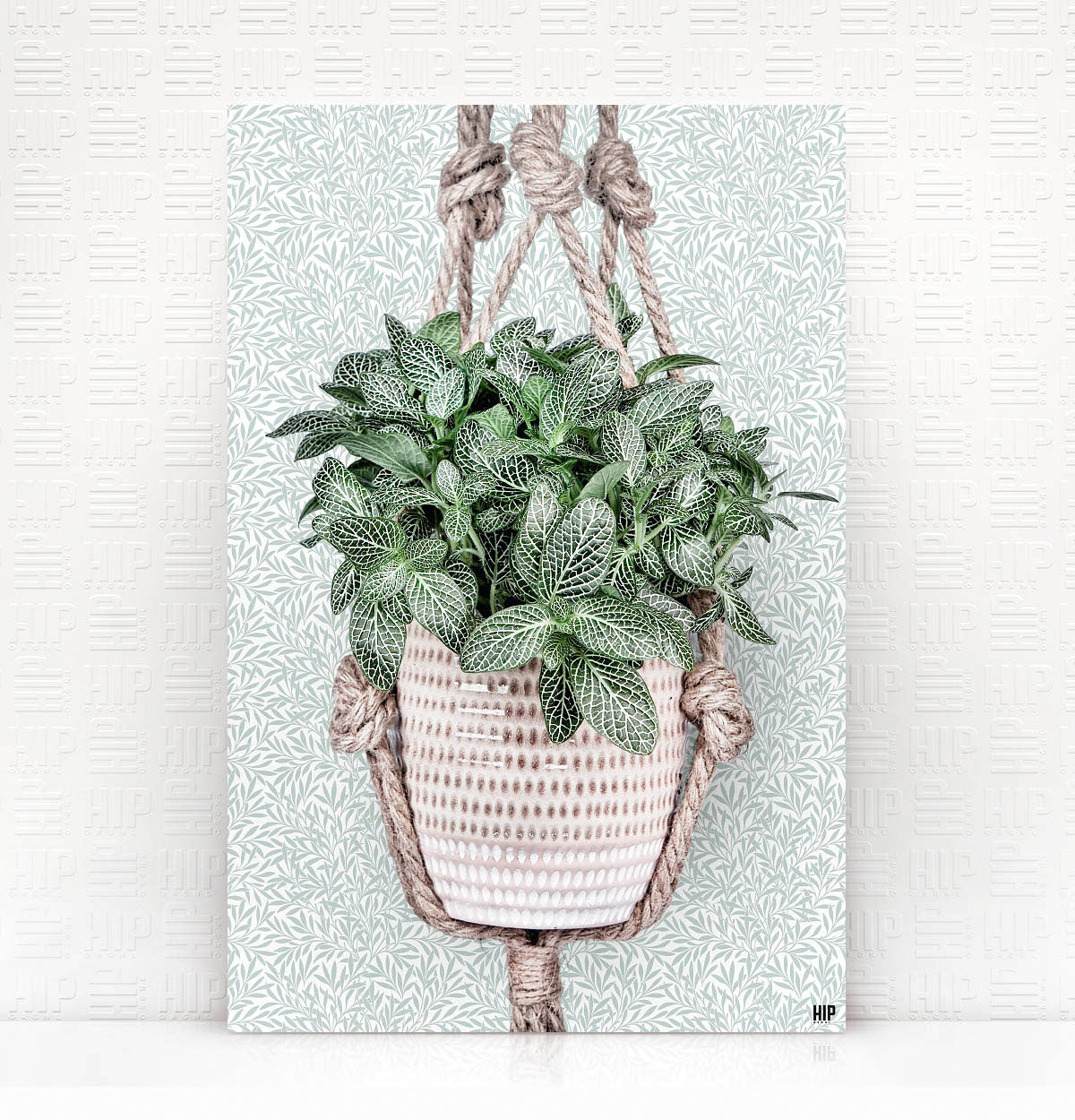 Vierkante wanddecoratie van een hangplant erop.