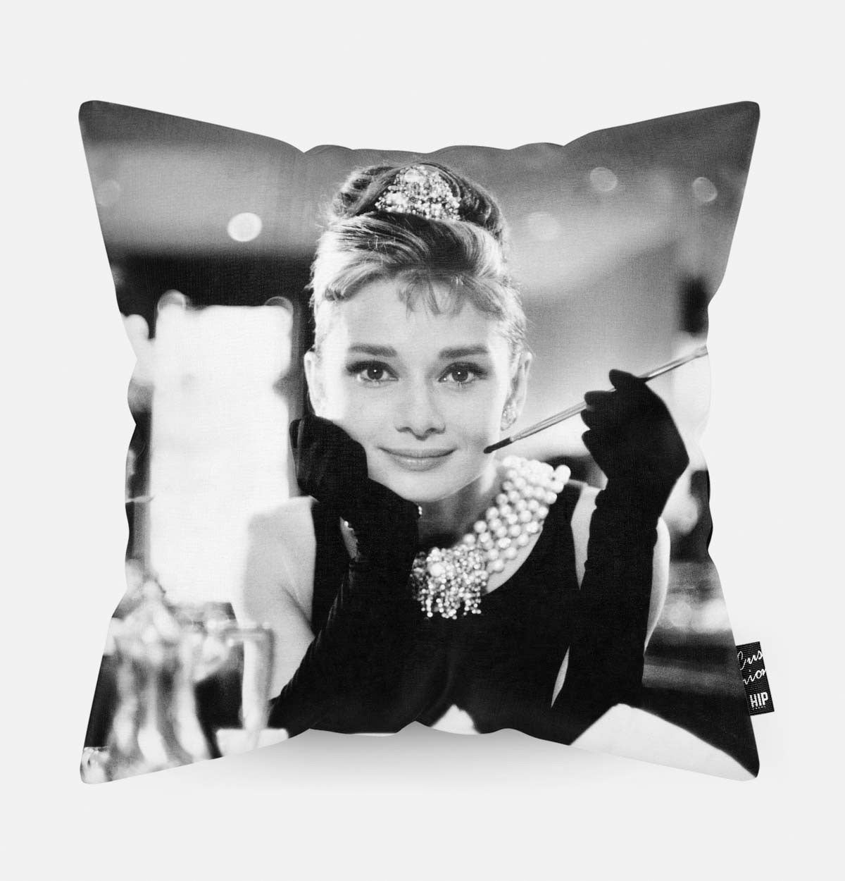 Audrey Hepburn met een sigaret in haar hand op ene kussen aan het ontbijt
