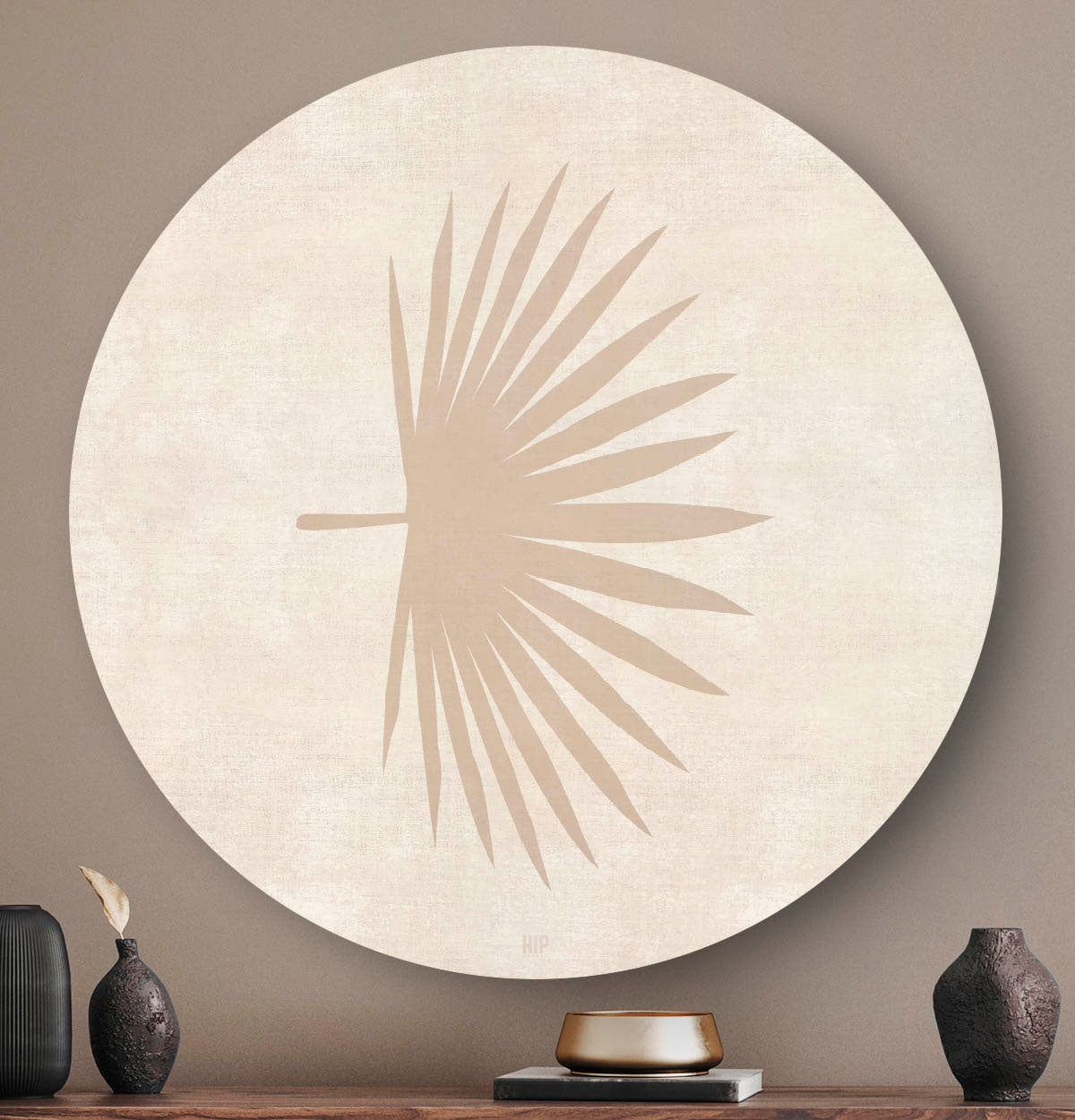 Wandcirkel met een abstract palmblad en een lichte achtergrond boven een houten dressoir