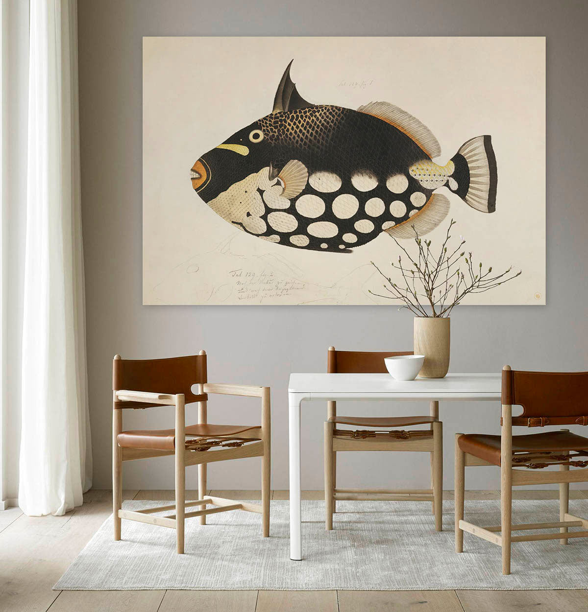 Schilderij met een zwart bruine vis tegen een muur met stoelen en een tafel er voor