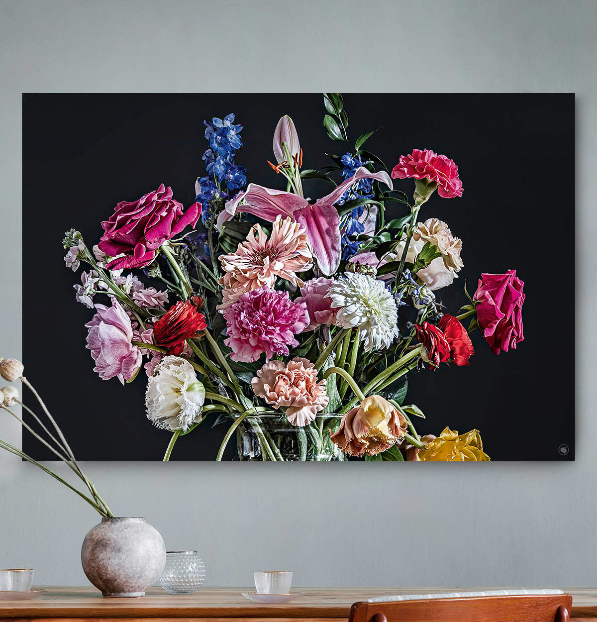 Schilderij met kleurrijke bloemen in een glazen vaas tegen een grijze muur