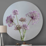 Wandcirkel met paarse bloemen en een grijze achtergrond tegen een muur met een tafellamp
