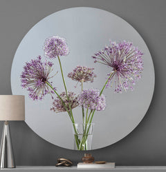 Wandcirkel met paarse bloemen en een grijze achtergrond tegen een muur met een tafellamp