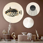 Drie ronde wanddecoraties met een vis en abstracte vormen tegen een taupe muur