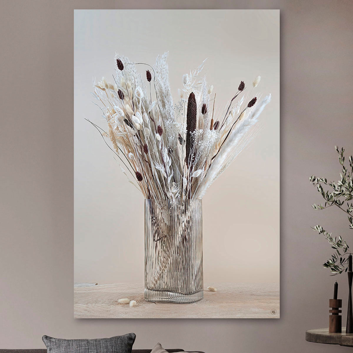 Schilderij met droogbloemen in glazen ribbel vaas tegen een lichte muur