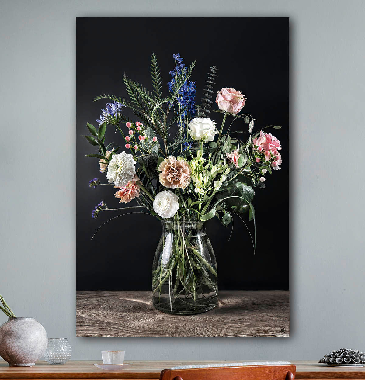 Schilderij met bloemen met zwarte achtergrond tegen een licht grijze muur