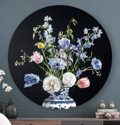Wandcirkel met lichtblauwe en witte bloemen met een donkere achtergrond tegen een donker grijze muur