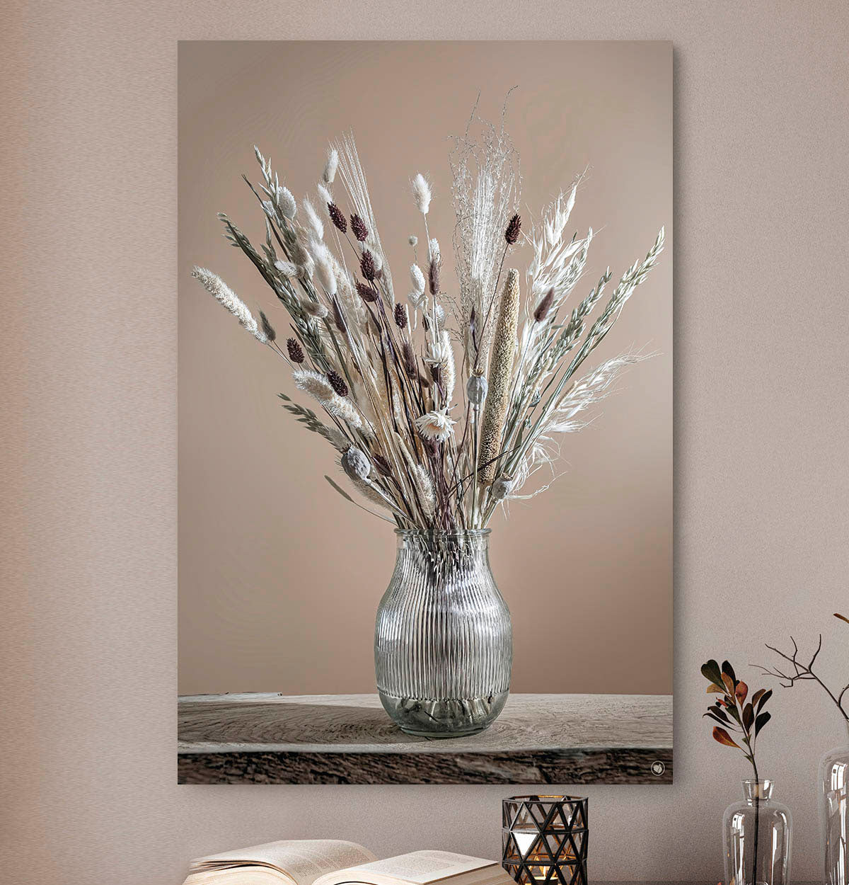 Wanddecoratie met witte en bruine droogbloemen in een glazen vaas tegen een beige muur