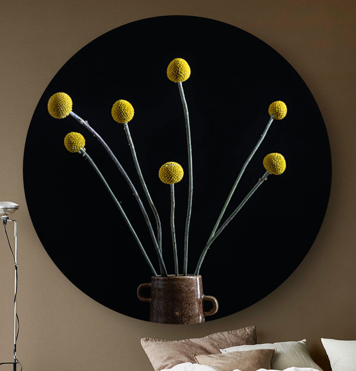 Muurcirkel met gele bol pluimen met een zwarte achtergrond tegen een beige muur