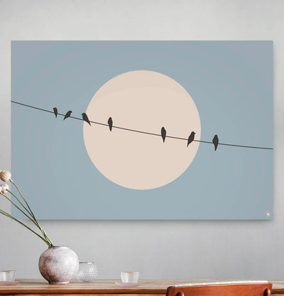 Vierkante wanddecoratie met vogels op een draad met de zon op de achtergrond erop.